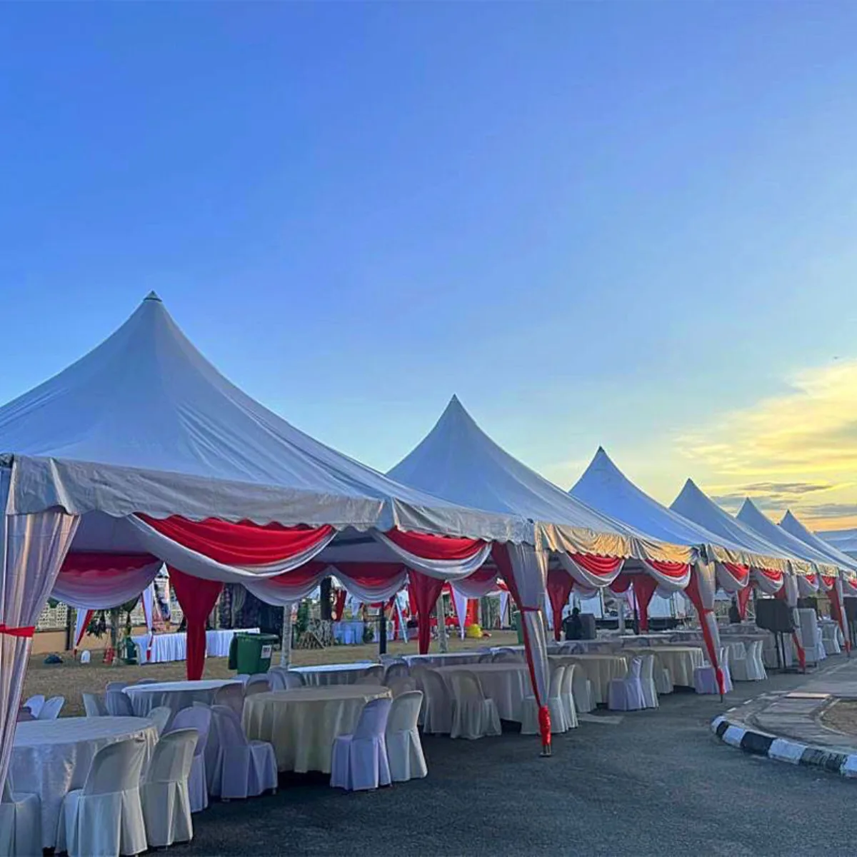 Series of peaked white canopies dressed for guests at dusk