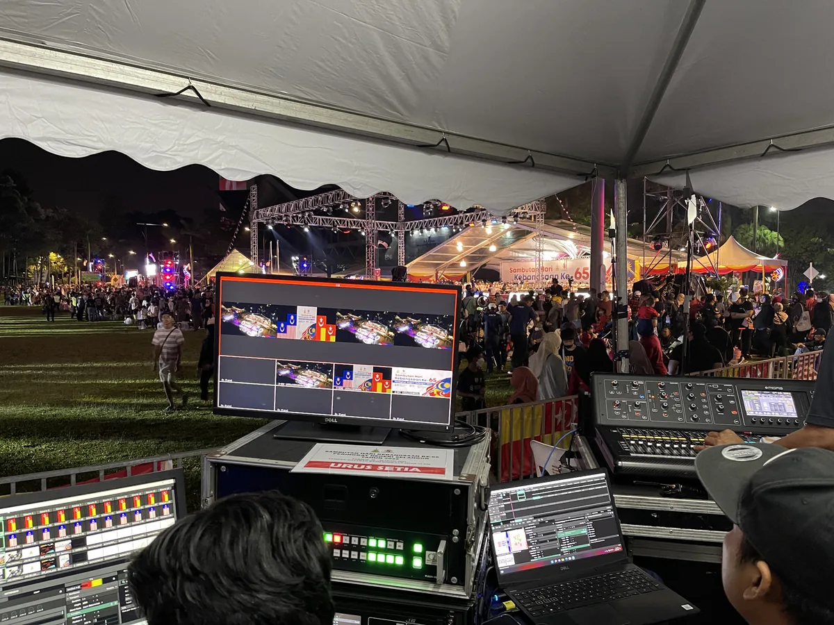 Video switcher and monitors at a control desk facing an outdoor event