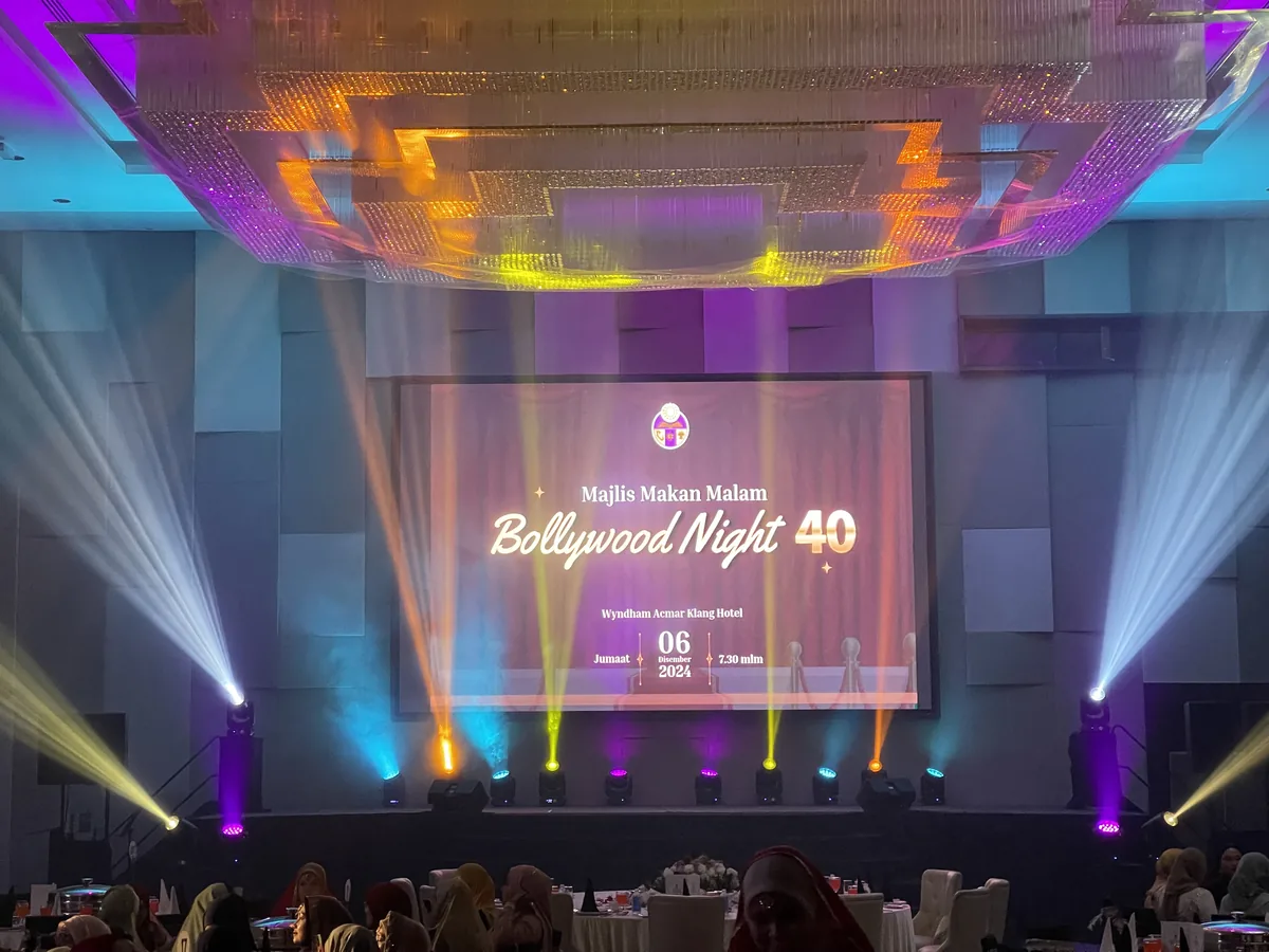 Orange and white beams fanning out around a ballroom stage screen
