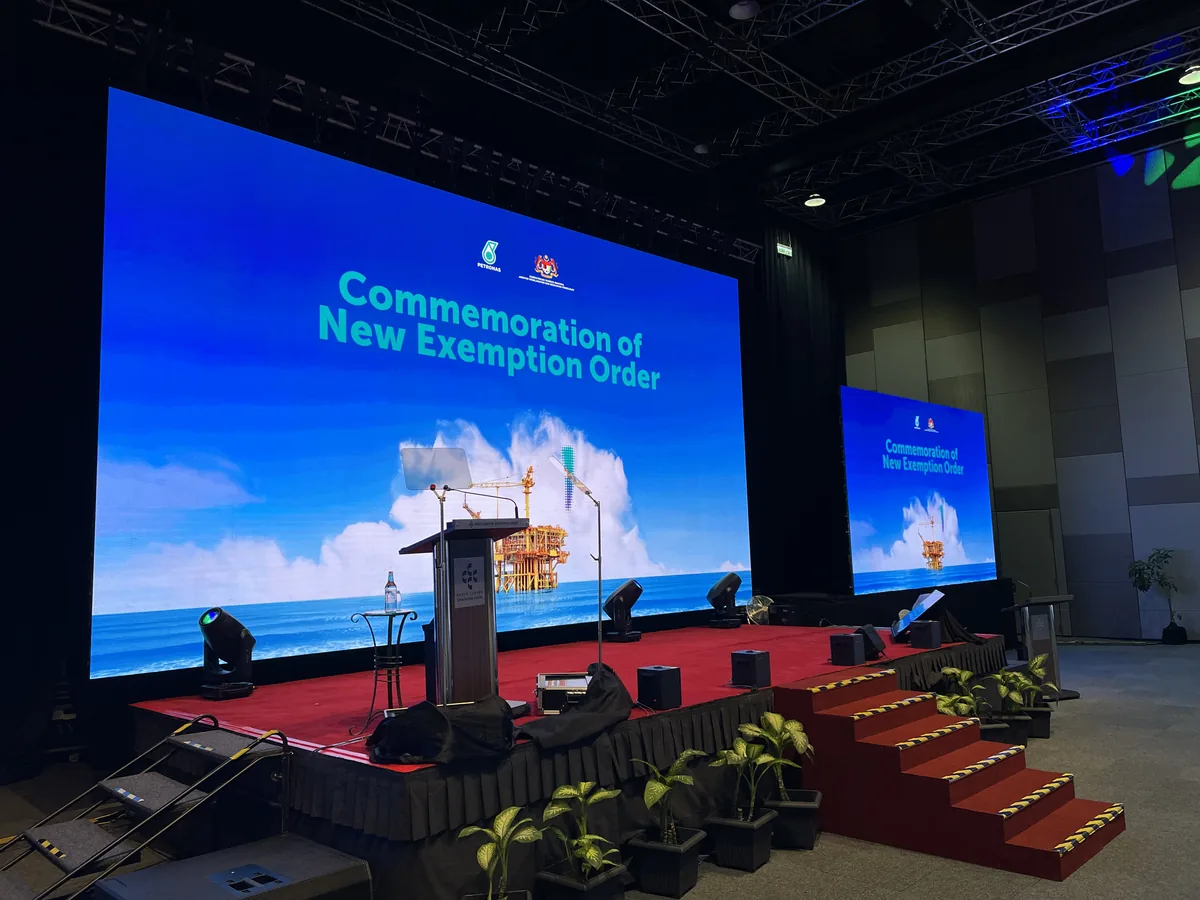 Conference stage with a wide LED screen, podium and red-carpeted steps