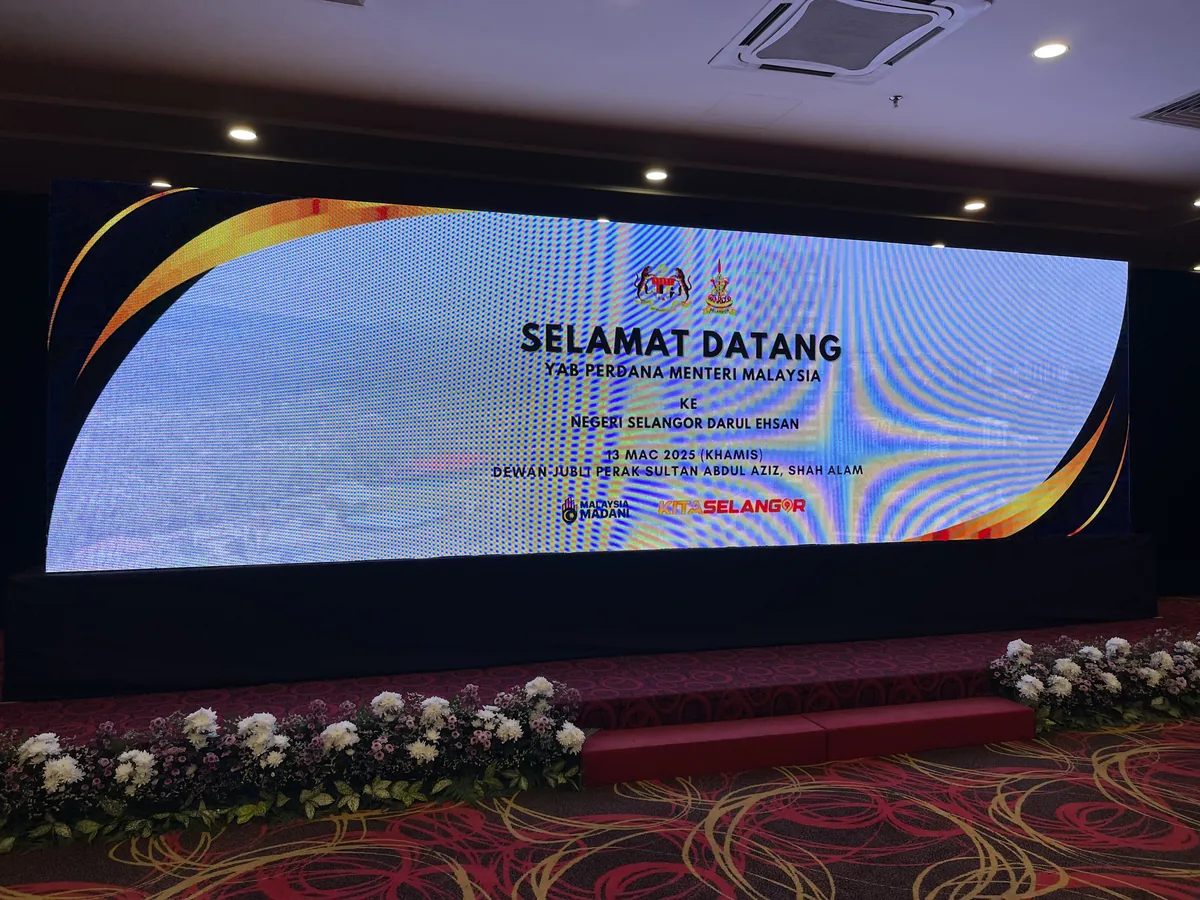 Curved LED welcome screen above a flower-lined stage