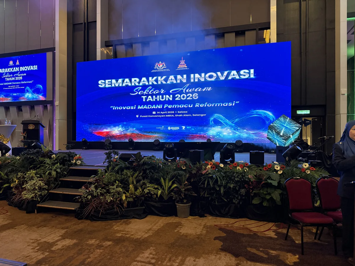 LED screen with an event title above stage steps and plants