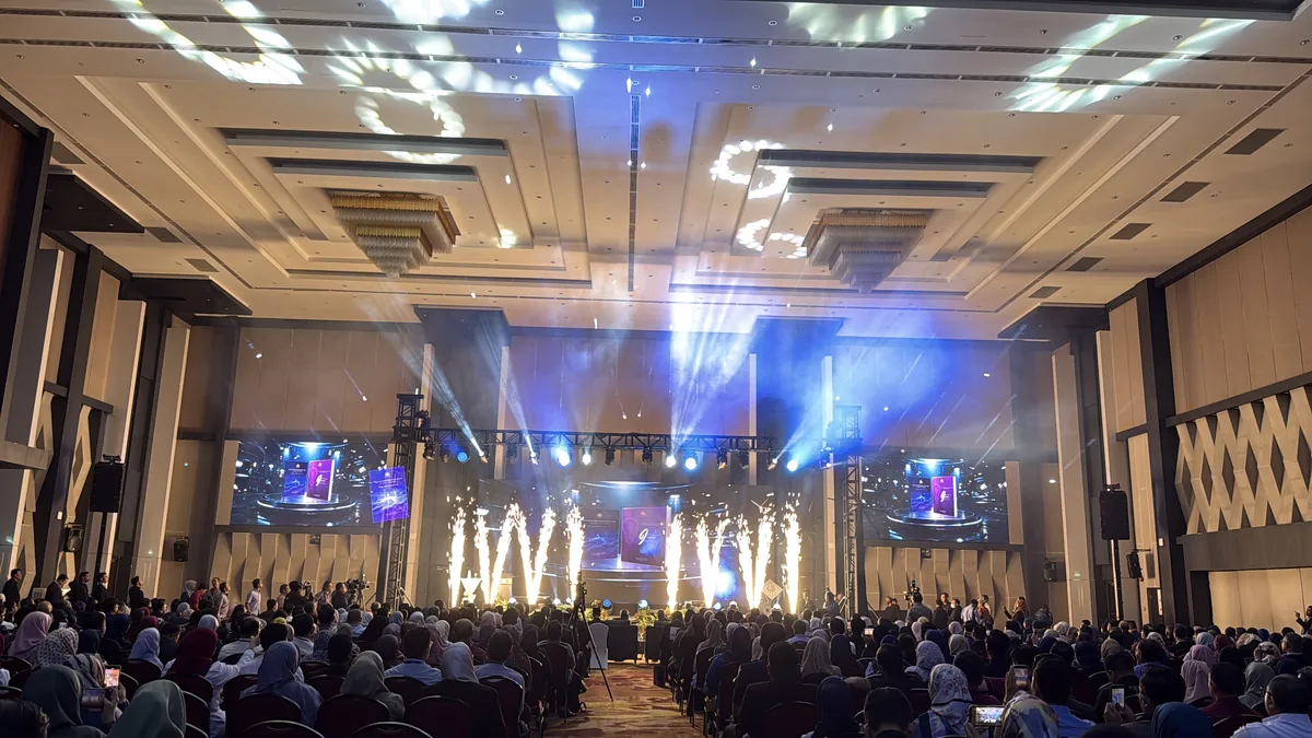 Stage sparks and ceiling light patterns above a seated audience