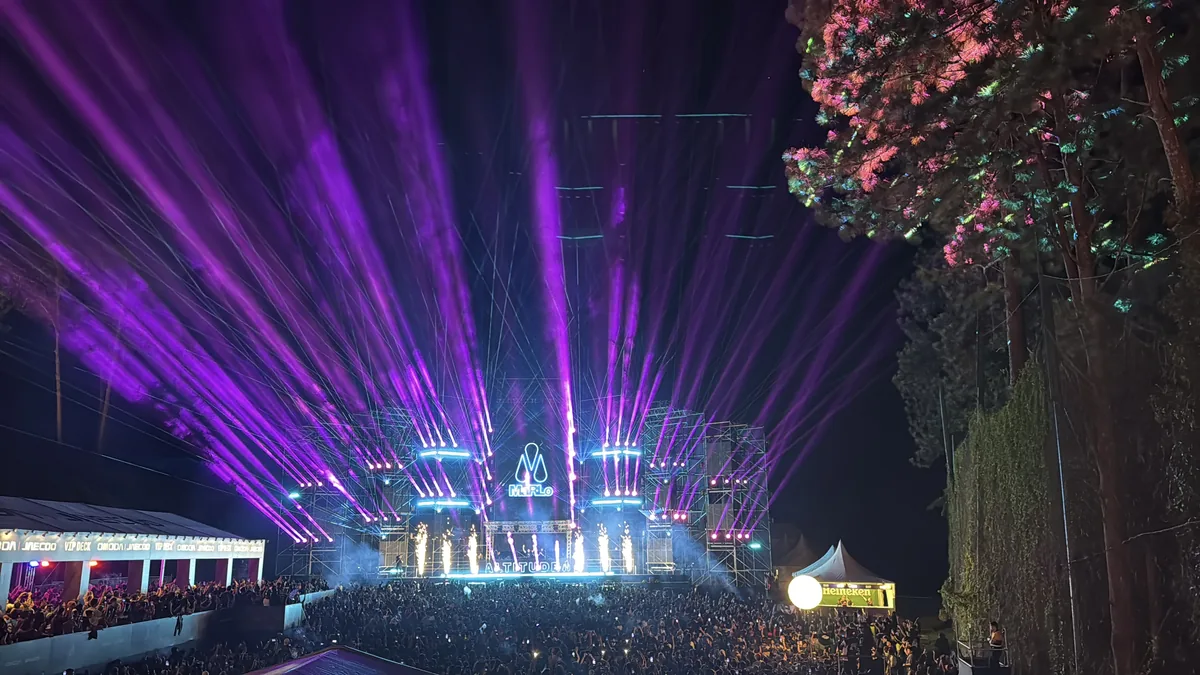 Purple laser beams over an outdoor night stage and crowd