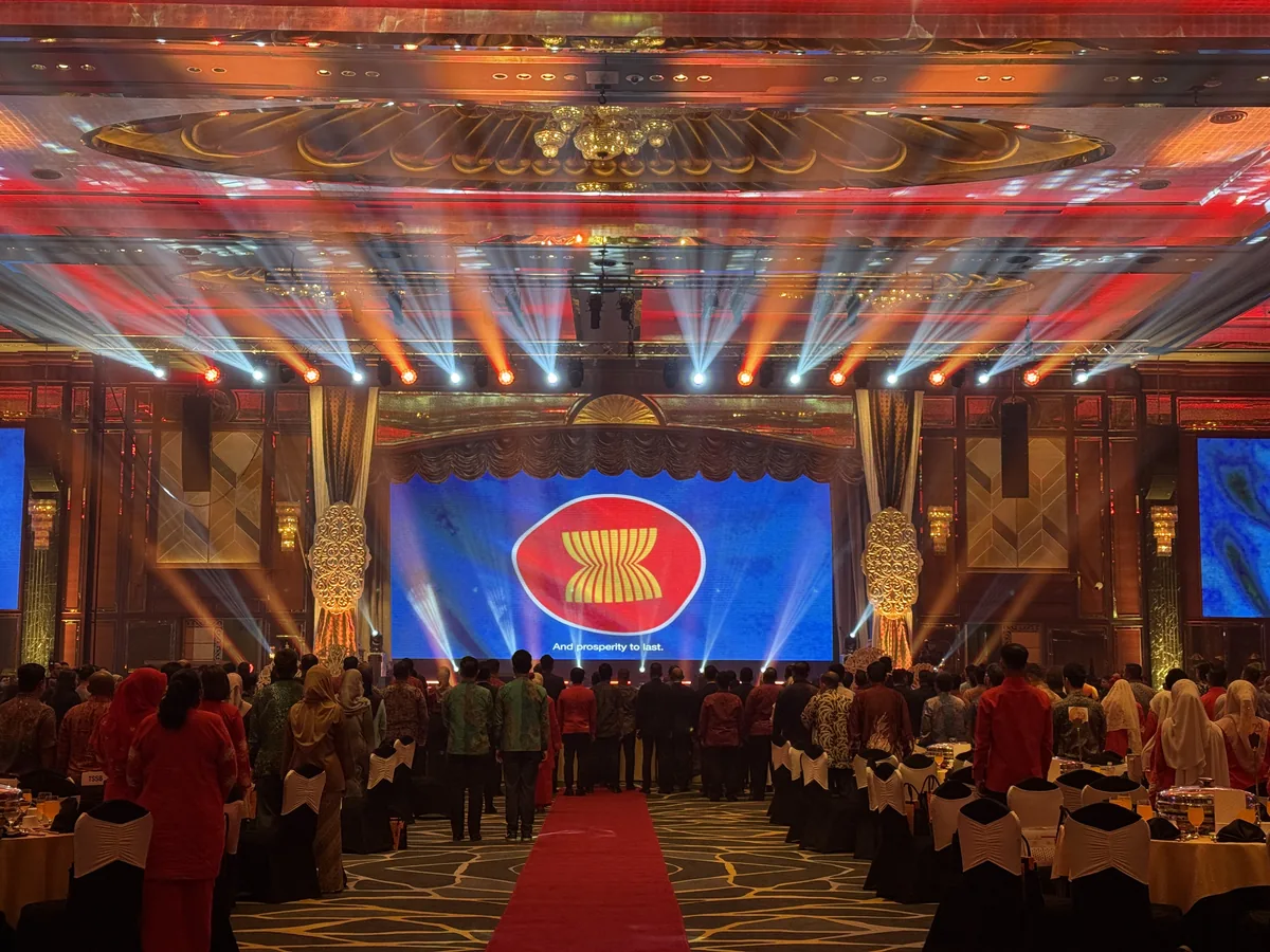 Gala stage with a large LED screen under coloured beams as guests stand