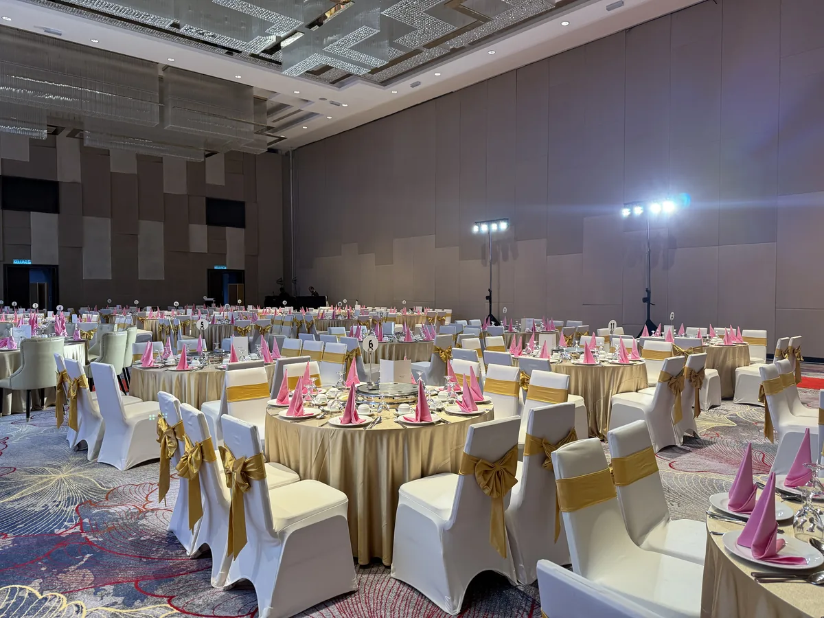 Banquet hall set with gold-sashed chairs and pink napkins